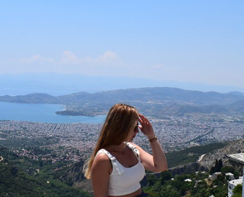 A person stands on a hill, overlooking a city and body of water.